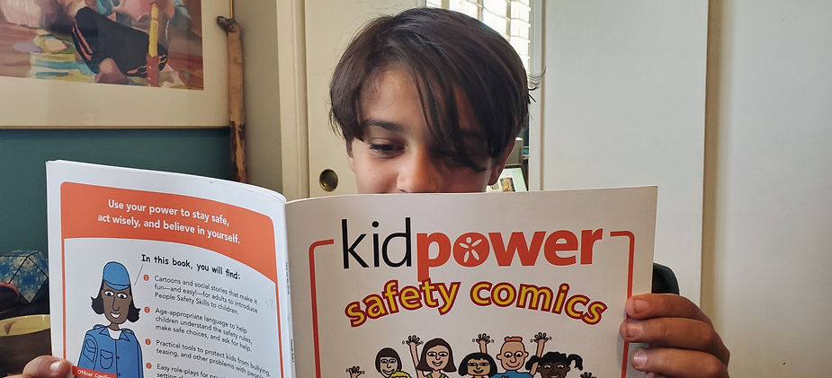 An 11 year old boy reading a book called Kidpower Safety Comics